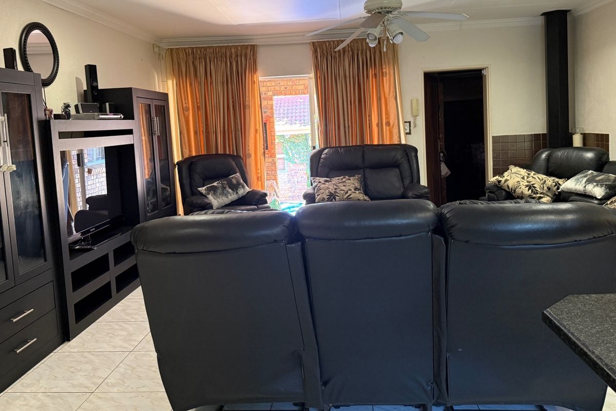 Spacious living room featuring tiled flooring, a ceiling fan, and a built-in fireplace, with direct access to the outdoor area via a sliding door.