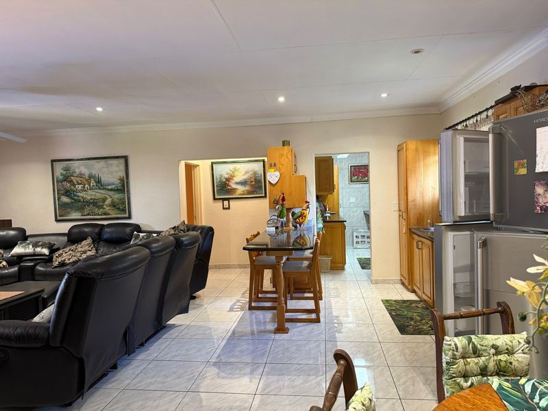 Open plan living area featuring tiled flooring, recessed lighting, and a breakfast bar, with direct access to a functional scullery area.