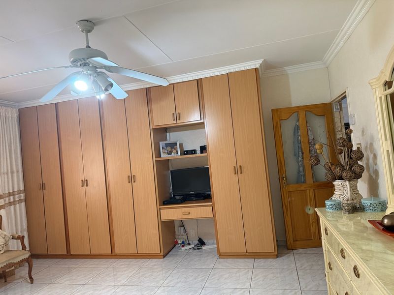 A bedroom featuring extensive built-in wooden cabinetry, a ceiling fan, and tiled flooring, offering ample storage space.