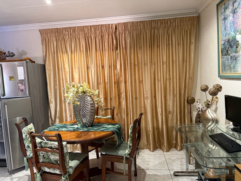 A dining area featuring tiled flooring and decorative ceiling cornicing, currently utilized as a multi-purpose space.