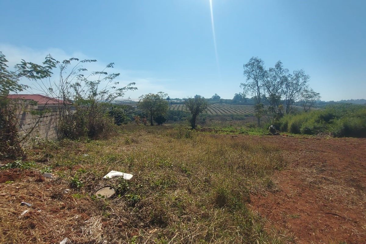 A vacant residential plot featuring natural terrain, boundary walling, and distant landscape views.