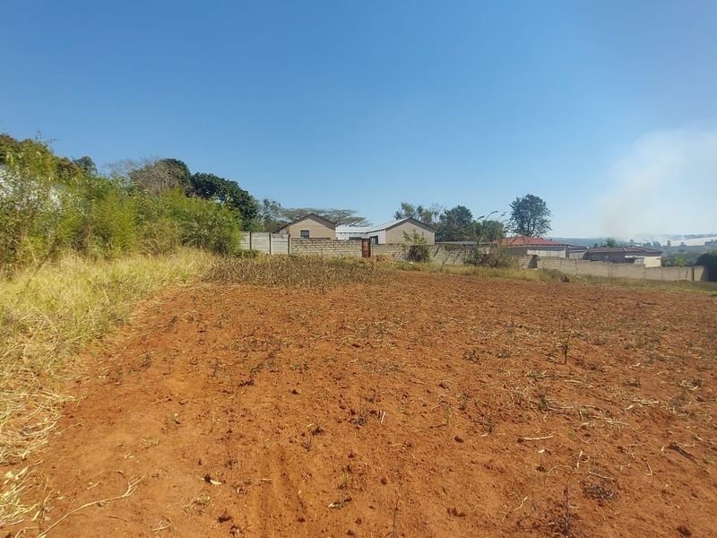 A view of a vacant residential plot featuring cleared soil and a perimeter boundary wall, suitable for future development.