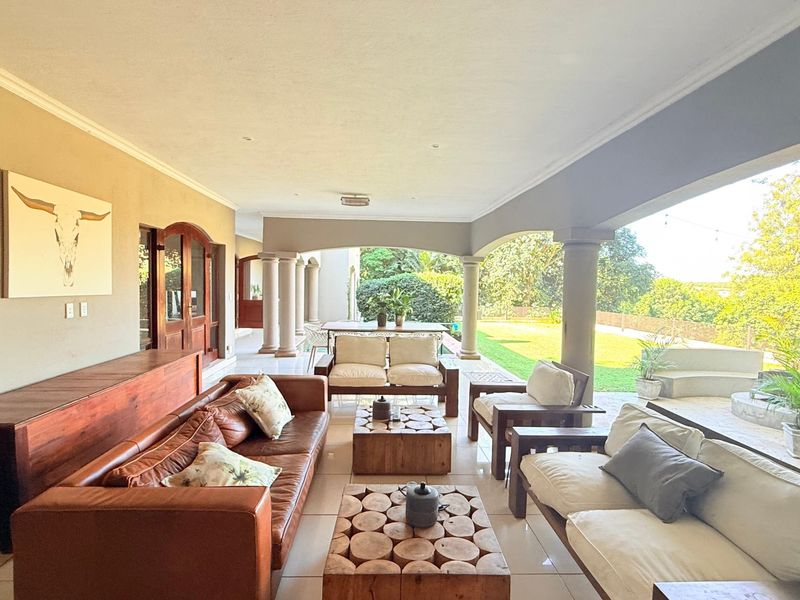 Spacious covered patio featuring tiled flooring, arched columns, and direct access to the garden, providing an ideal area for outdoor entertaining.