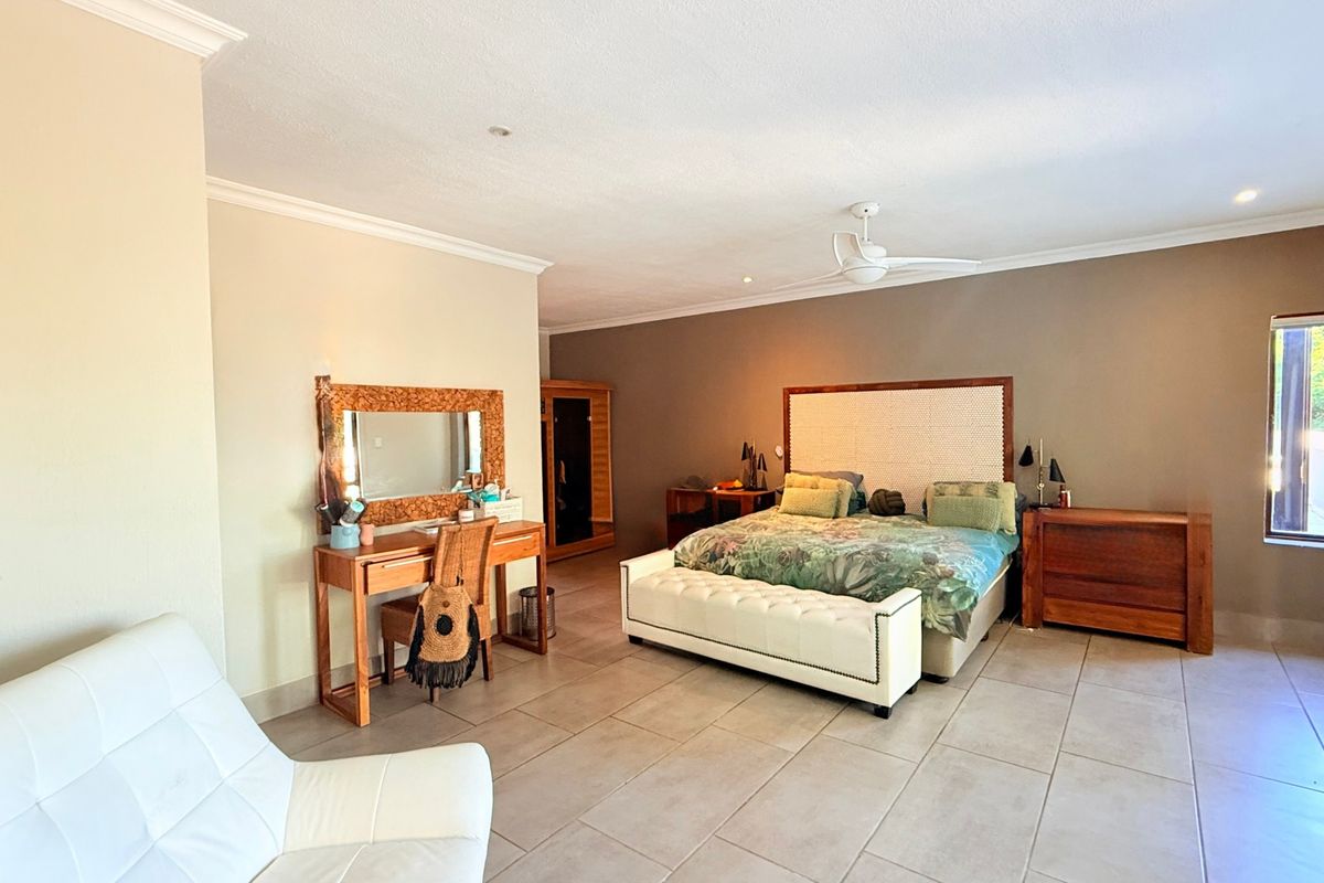 Spacious bedroom featuring neutral wall tones, large format floor tiles, and a ceiling fan, offering a comfortable and well-maintained living space.