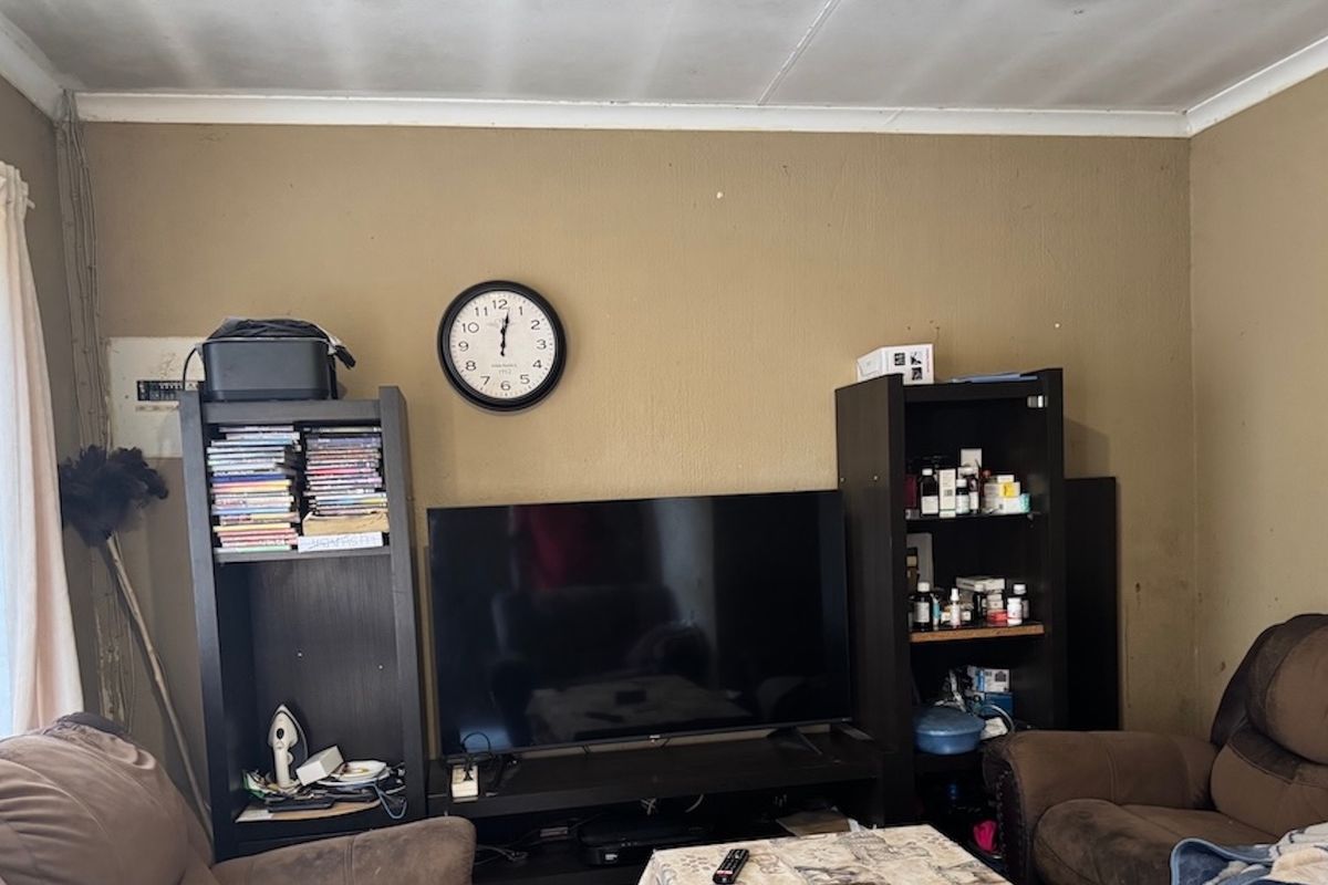 A living room area featuring a visible electrical distribution board and standard wall finishes, currently showing signs of wear on the walls and ceiling.