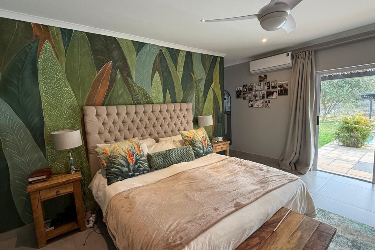 Spacious bedroom featuring a feature wall, split-system air conditioning, ceiling fan, and direct access to the outdoor patio and pool area through sliding doors.