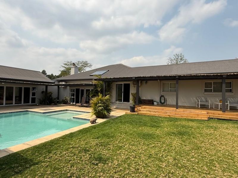 Spacious rear exterior featuring a swimming pool, timber decking, and a covered patio area, ideal for outdoor entertaining.
