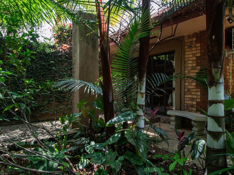 A private rear garden area featuring a paved patio, brick exterior wall, and an installed air conditioning unit.