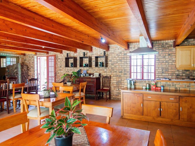 Spacious open-plan living and kitchen area featuring exposed timber ceiling beams, rustic brick walls, and warm wooden cabinetry throughout.