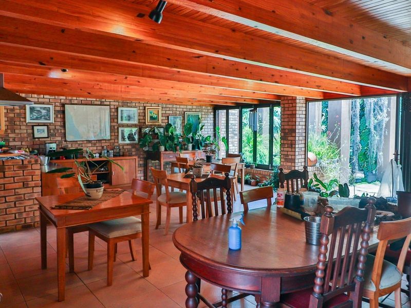 Spacious open-plan living and dining area featuring exposed timber beams, face brick walls, and large sliding doors providing seamless access to the garden.