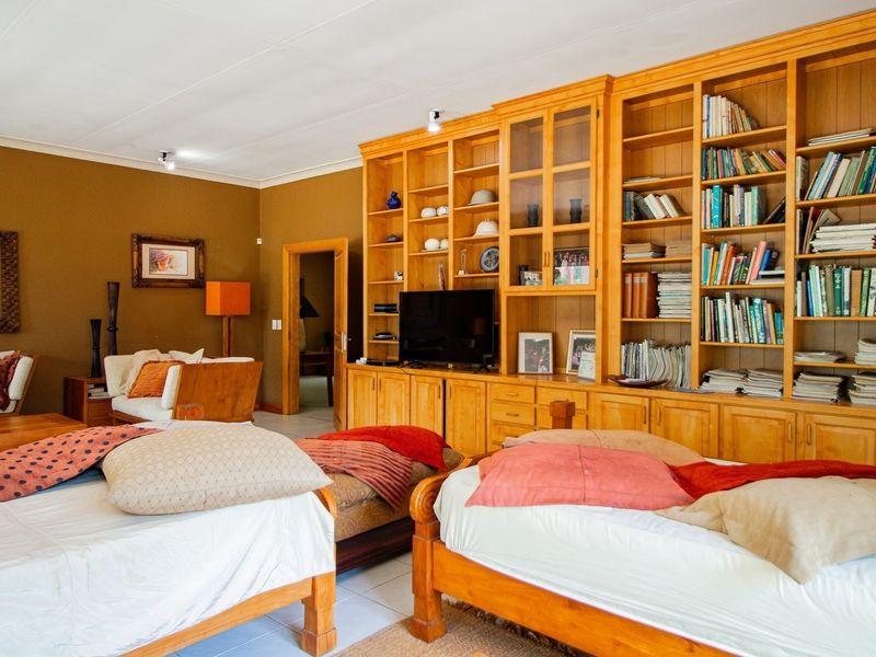 Spacious bedroom featuring a large built-in wooden shelving unit and tiled flooring, offering ample storage and a comfortable layout.