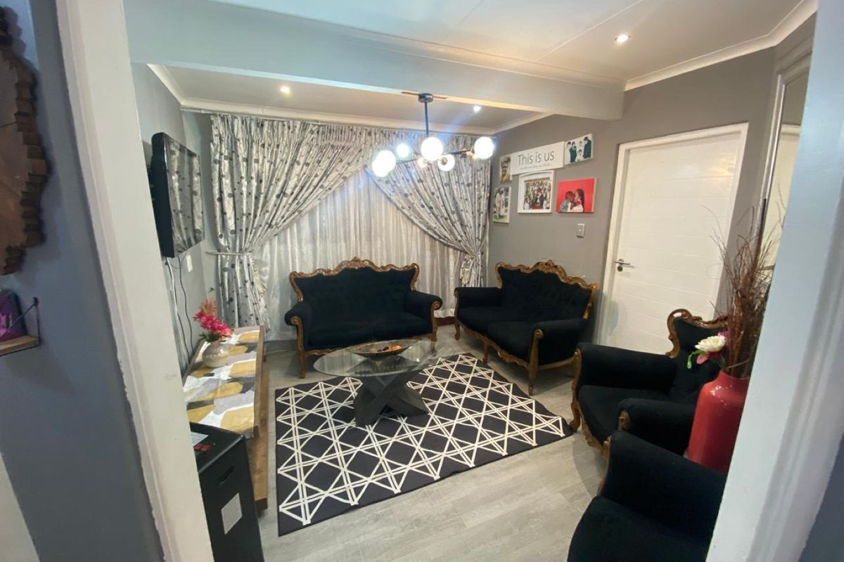 A well-maintained living room featuring modern laminate flooring, recessed downlighting, and coved ceiling finishes, providing a comfortable and functional space.