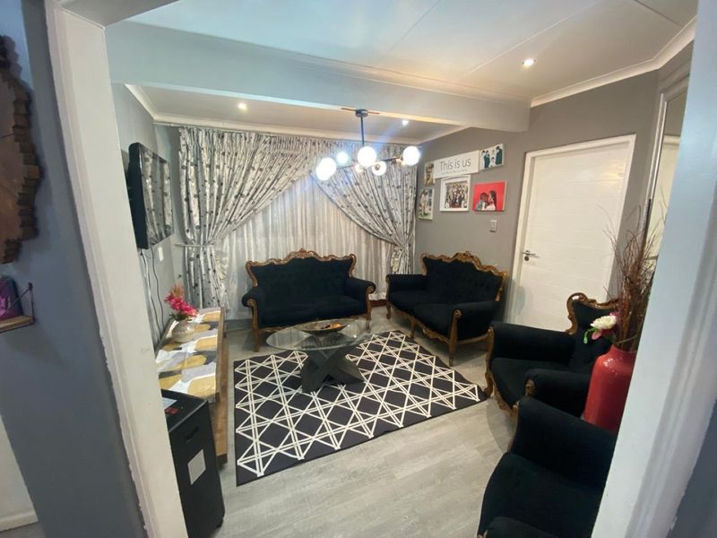 A well-maintained living room featuring modern laminate flooring, recessed downlighting, and coved ceiling finishes, providing a comfortable and functional space.
