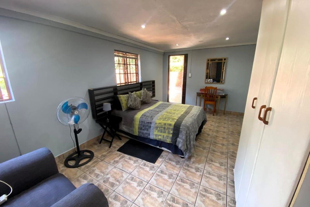 A bedroom featuring tiled flooring, built-in cupboards, and recessed downlights, with direct access to an outdoor area.