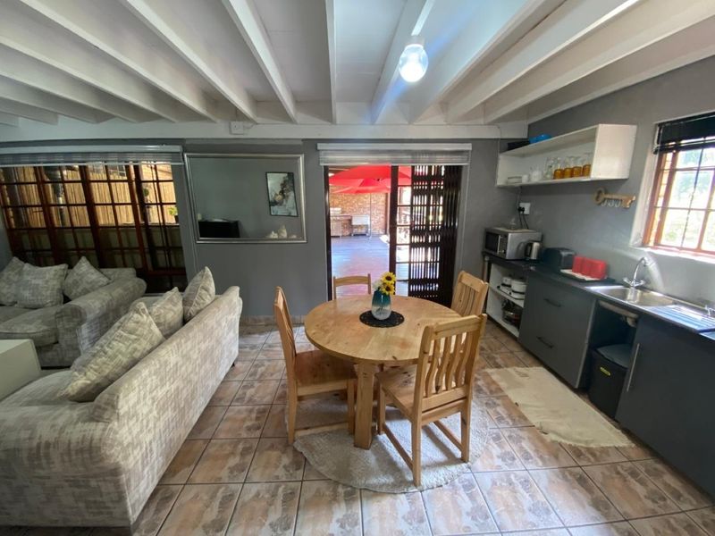 Open plan living and kitchen area featuring exposed beam ceilings, tiled flooring, and direct access to an outdoor patio space.