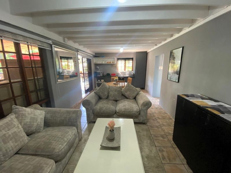 Open-plan living and kitchen area featuring exposed beam ceilings, tiled flooring, and direct access to an outdoor patio through sliding glass doors.