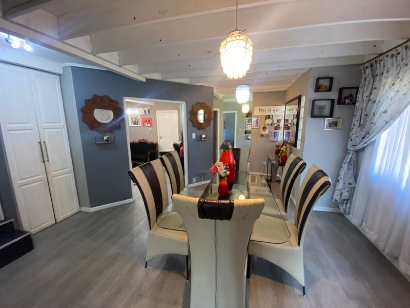 Dining room featuring exposed timber ceiling beams, modern laminate flooring, and pendant lighting, creating a bright and functional space for family meals.