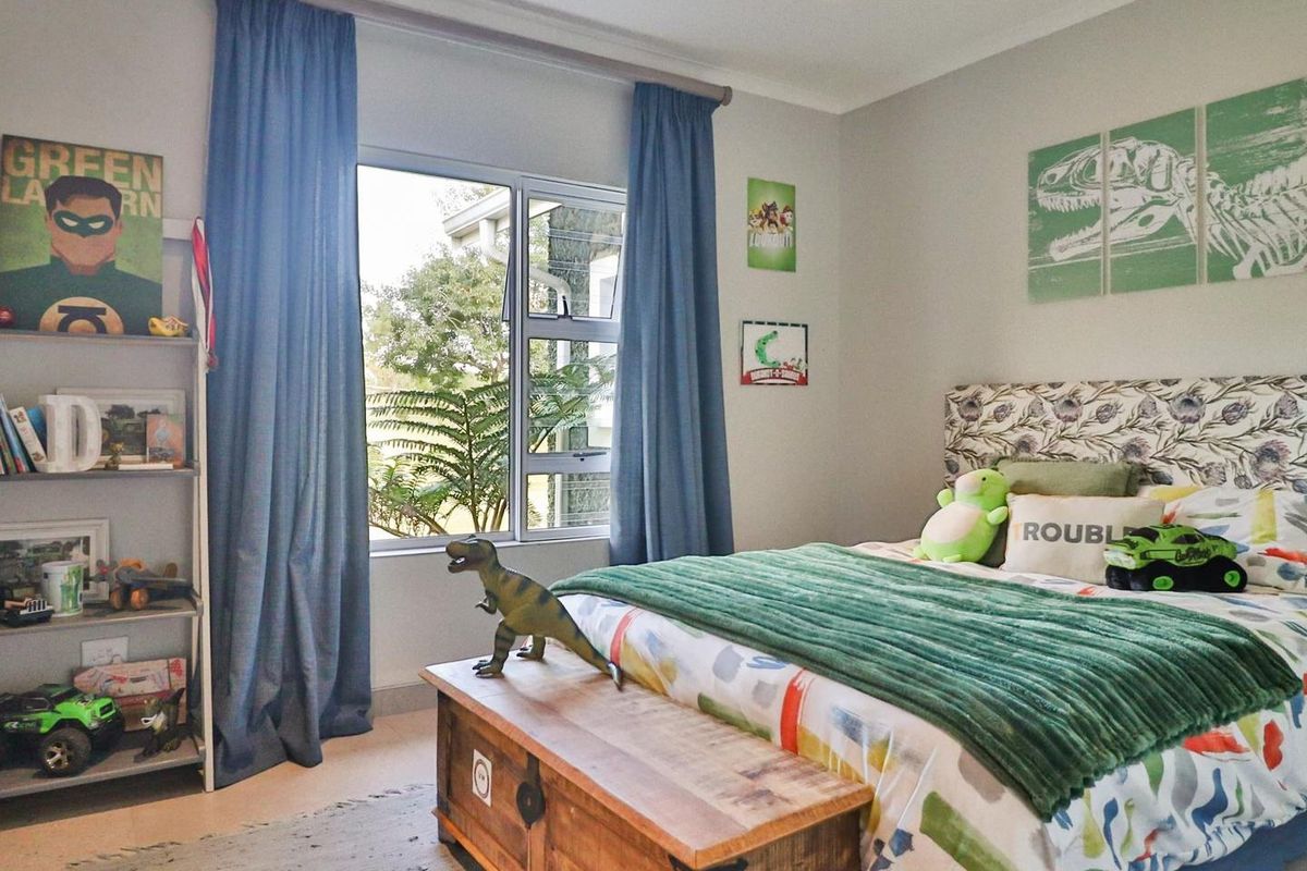 A well-maintained bedroom featuring neutral wall finishes, recessed downlighting, and an aluminium-framed window with views of the garden.