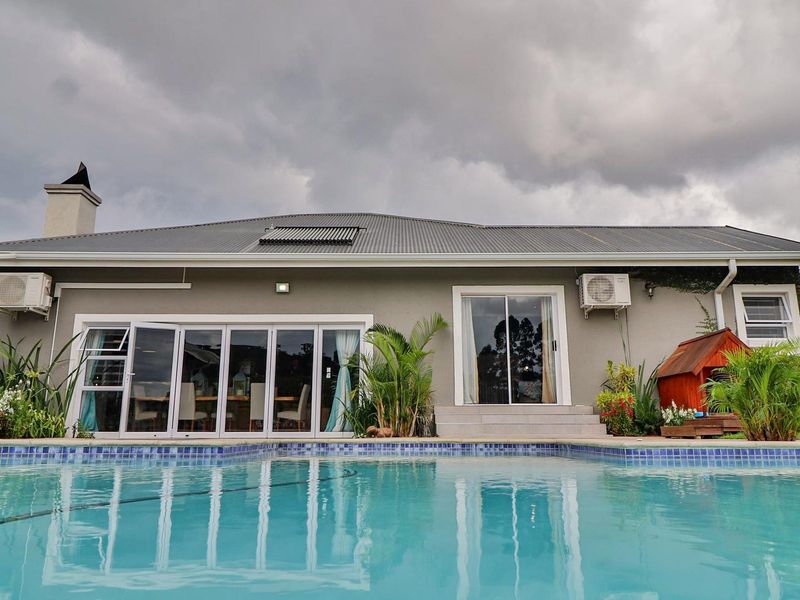 Rear view of the property featuring a swimming pool, solar water heating, and direct access to the interior via bi-fold and sliding glass doors.
