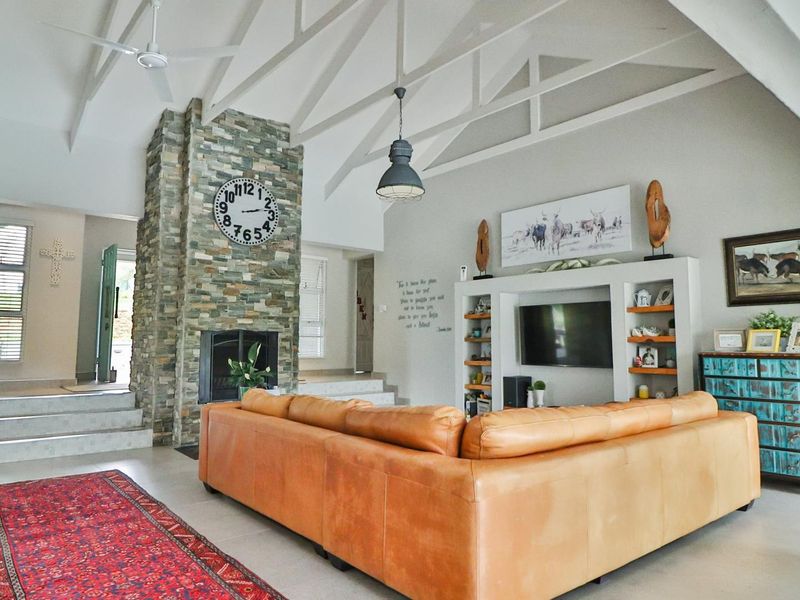 Spacious living room featuring a vaulted ceiling, a prominent stone fireplace, and custom built-in shelving units.