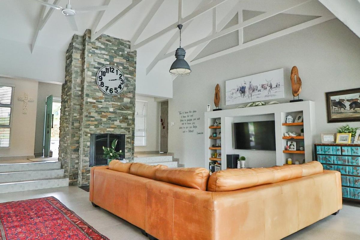 Spacious living room featuring a vaulted ceiling, a prominent stone fireplace, and custom built-in shelving units.