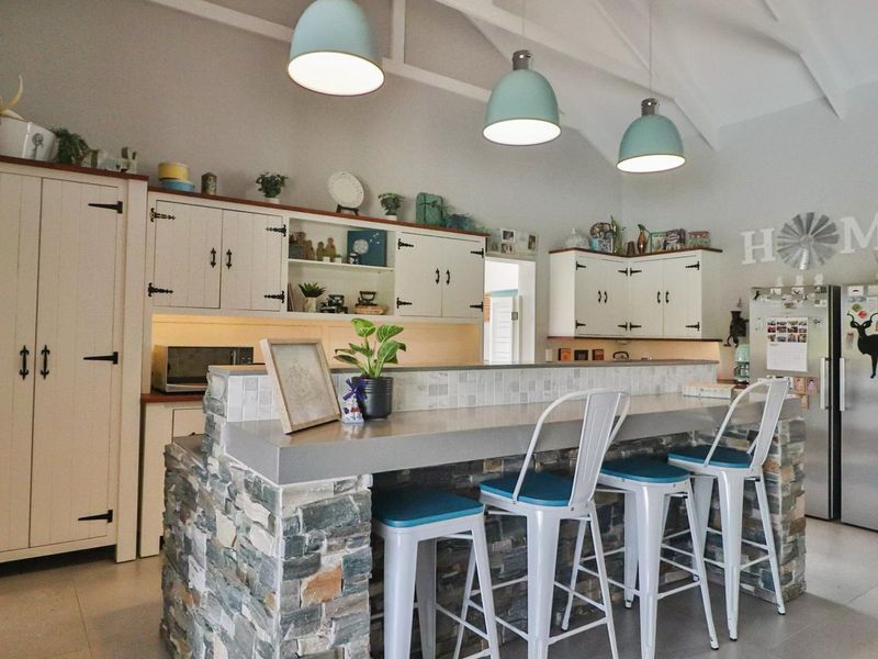 A charming kitchen featuring a stone-clad breakfast bar, custom cabinetry, vaulted ceilings, and stylish pendant lighting, creating a warm and inviting culinary space.