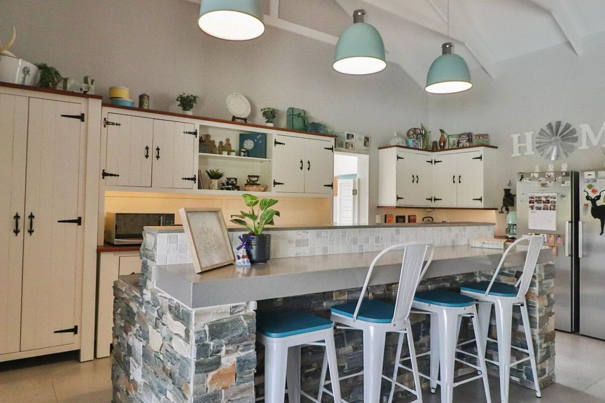 A charming kitchen featuring a stone-clad breakfast bar, custom cabinetry, vaulted ceilings, and stylish pendant lighting, creating a warm and inviting culinary space.