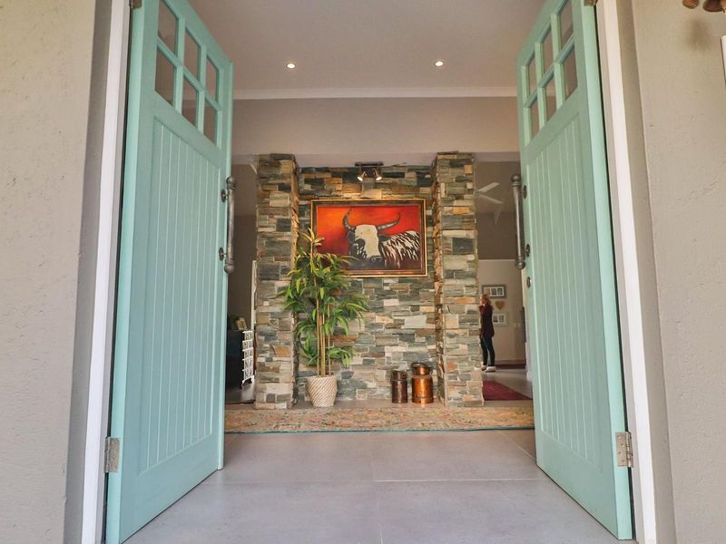 Welcoming entrance featuring double doors opening into a foyer with a prominent stone feature wall and modern tiled flooring.