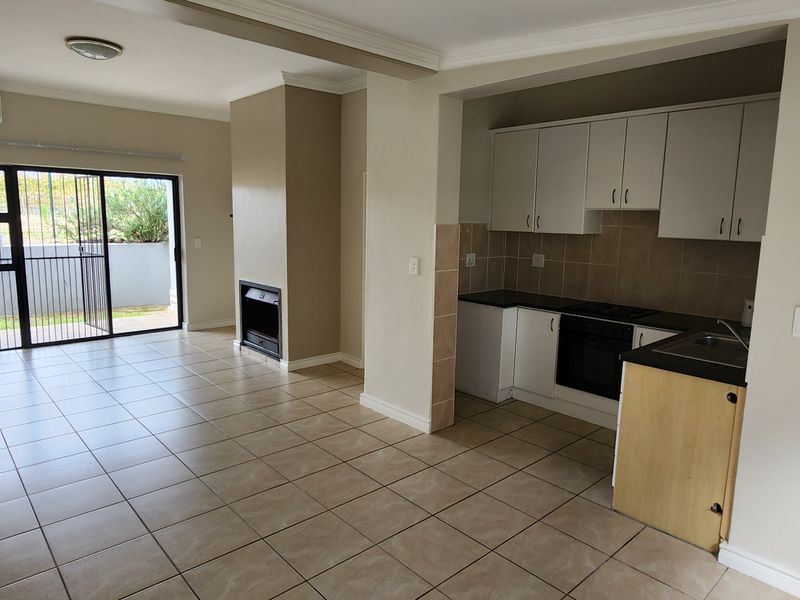 Open-plan living area featuring tiled floors, a built-in fireplace, air conditioning, and a functional kitchen with built-in appliances and cabinetry.