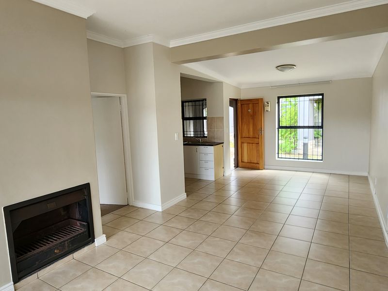 Spacious open-plan living area featuring tiled floors, a built-in fireplace, and an adjoining kitchen space with neutral finishes.