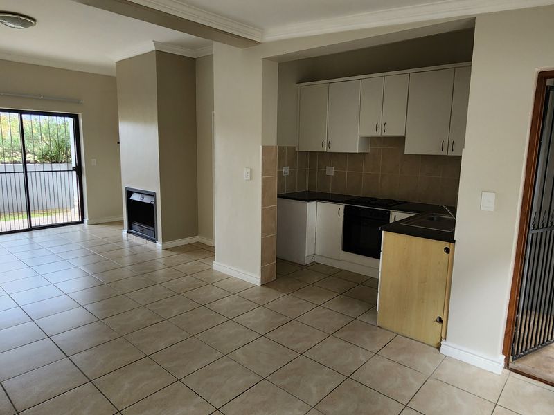 Open-plan living area featuring tiled floors, a built-in fireplace, air conditioning, and a functional kitchen with built-in appliances and direct outdoor access.
