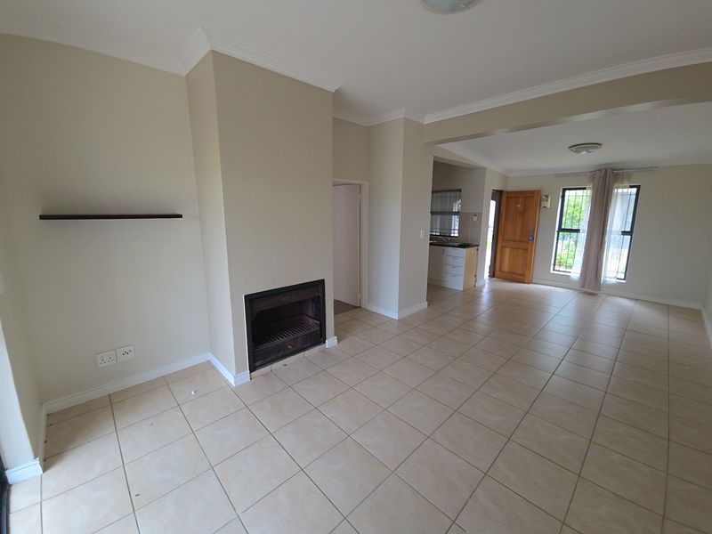 Spacious open-plan living area featuring ceramic floor tiles, a built-in fireplace, and direct access to the kitchen and entrance.