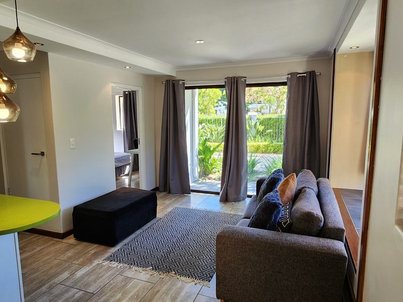 An open-plan living area featuring tiled flooring, recessed lighting, and a kitchen peninsula, with direct access to an outdoor patio through sliding glass doors.