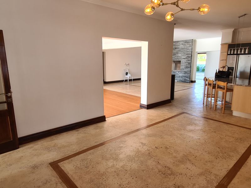 Spacious open-plan living area featuring stone flooring, a central kitchen island, and a stone fireplace, connecting seamlessly to adjacent living spaces.