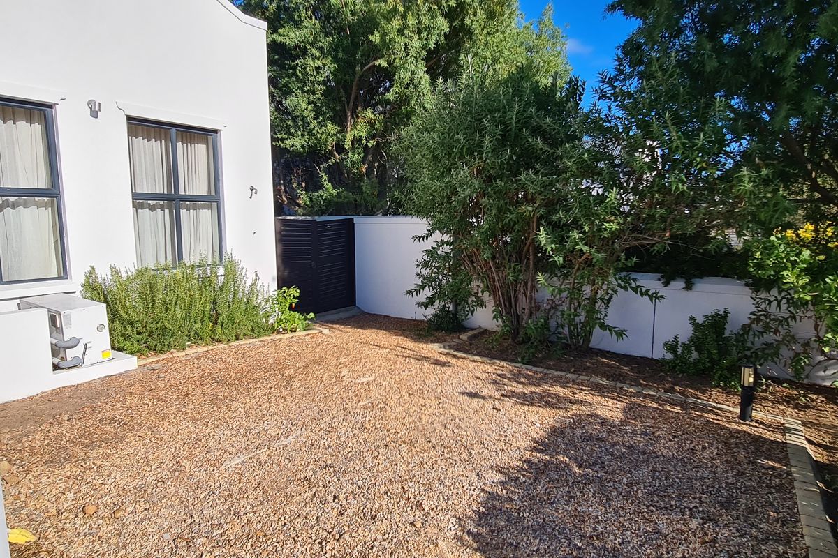A private rear courtyard featuring a gravel surface, boundary walls, and established greenery, providing a low-maintenance outdoor space.