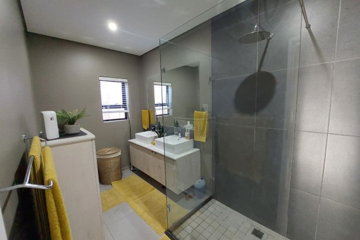 Modern bathroom featuring a double vanity with vessel sinks and a spacious walk-in shower with a frameless glass enclosure and rain shower head.