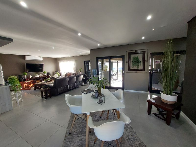 Spacious open-plan living and dining area featuring modern tiled flooring, recessed lighting, and large sliding glass doors leading to an outdoor space.