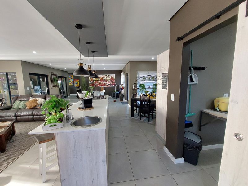 Spacious open-plan living area featuring a modern kitchen island with gas hob, tiled flooring, and a convenient walk-in pantry with sliding barn door.