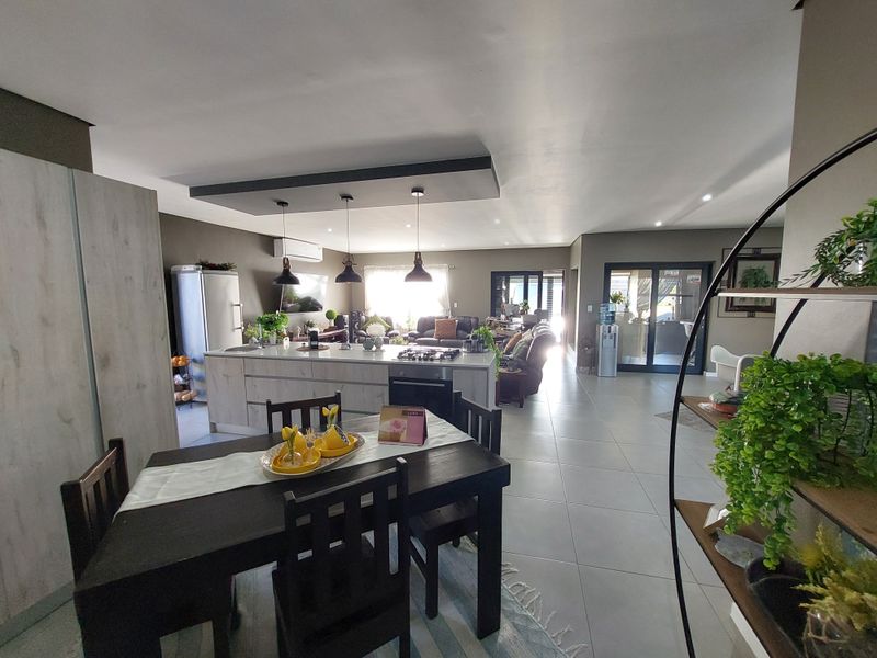 Spacious open-plan living area featuring a modern kitchen island with integrated hob and oven, tiled flooring, and seamless flow to the outdoor patio.