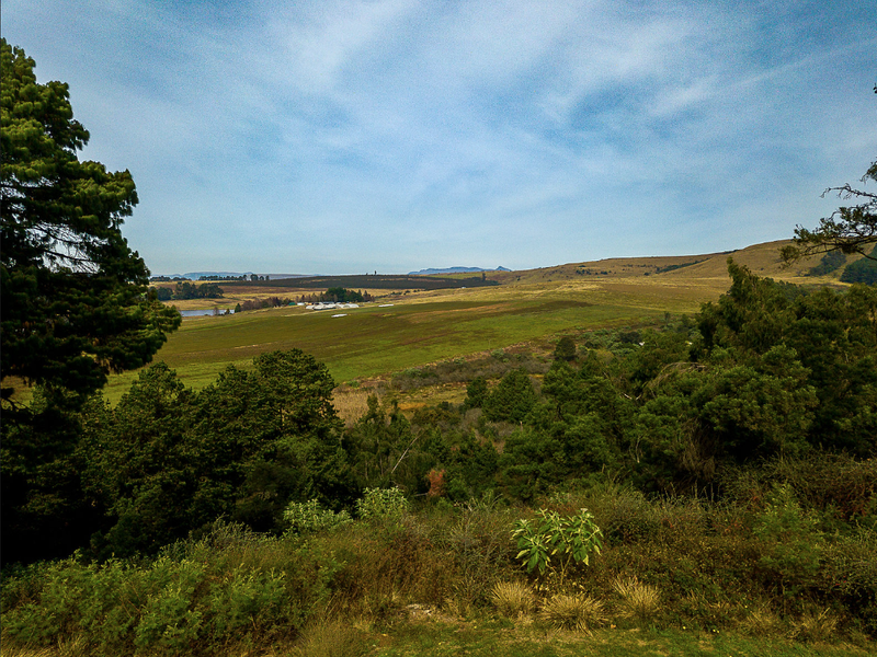 A scenic landscape view overlooking rolling hills, open fields, and natural vegetation, showcasing the property's expansive rural surroundings.