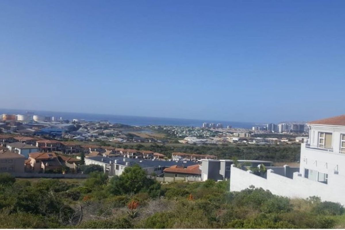 An elevated view overlooking a residential neighborhood with a distant coastal horizon and urban development.