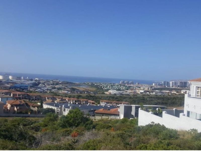 An elevated view overlooking a residential neighborhood with a distant coastal horizon and urban development.