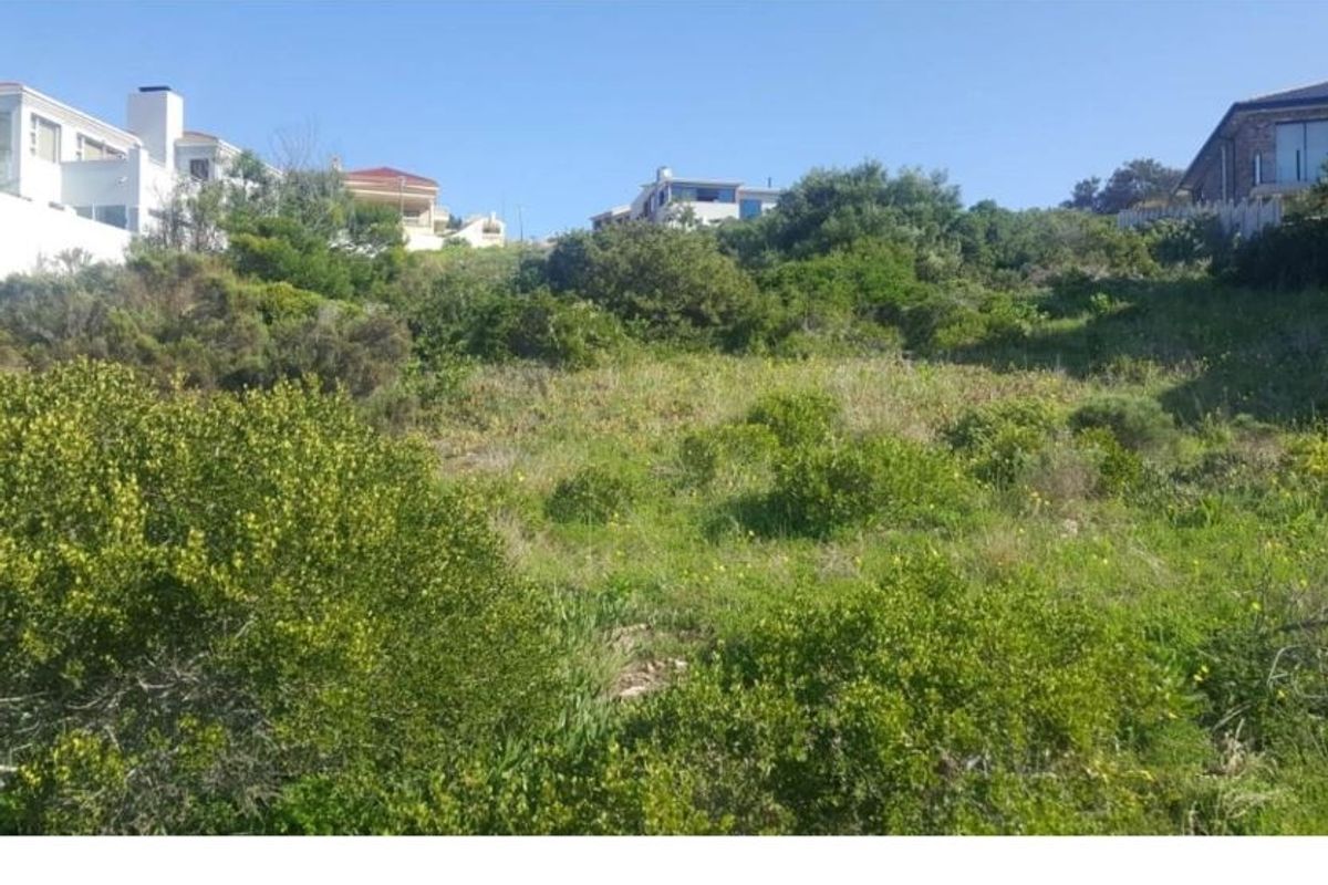 A sloped residential vacant land plot featuring natural vegetation and surrounding neighborhood views.