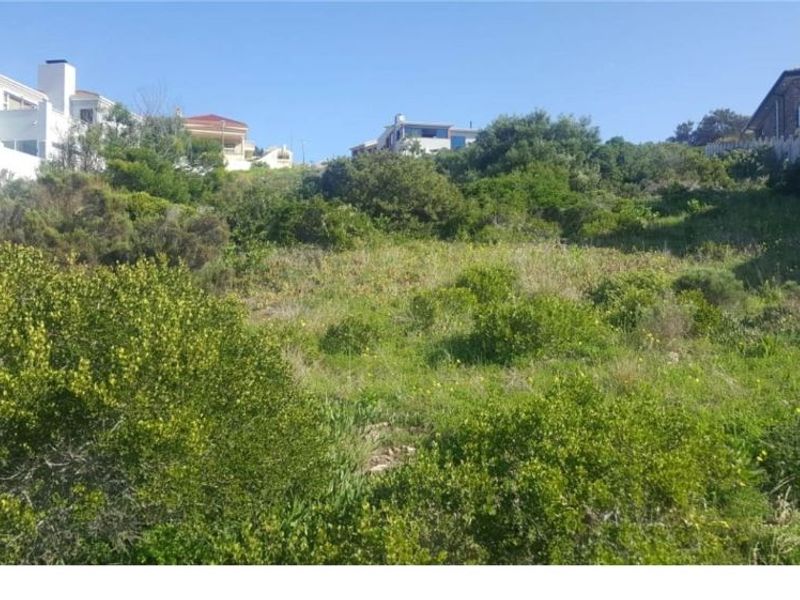 A sloped residential vacant land plot featuring natural vegetation and surrounding neighborhood views.