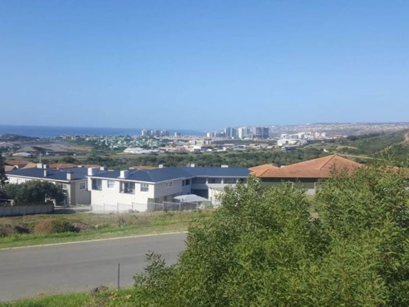 An elevated view overlooking the surrounding residential neighborhood, coastal landscape, and distant city skyline.