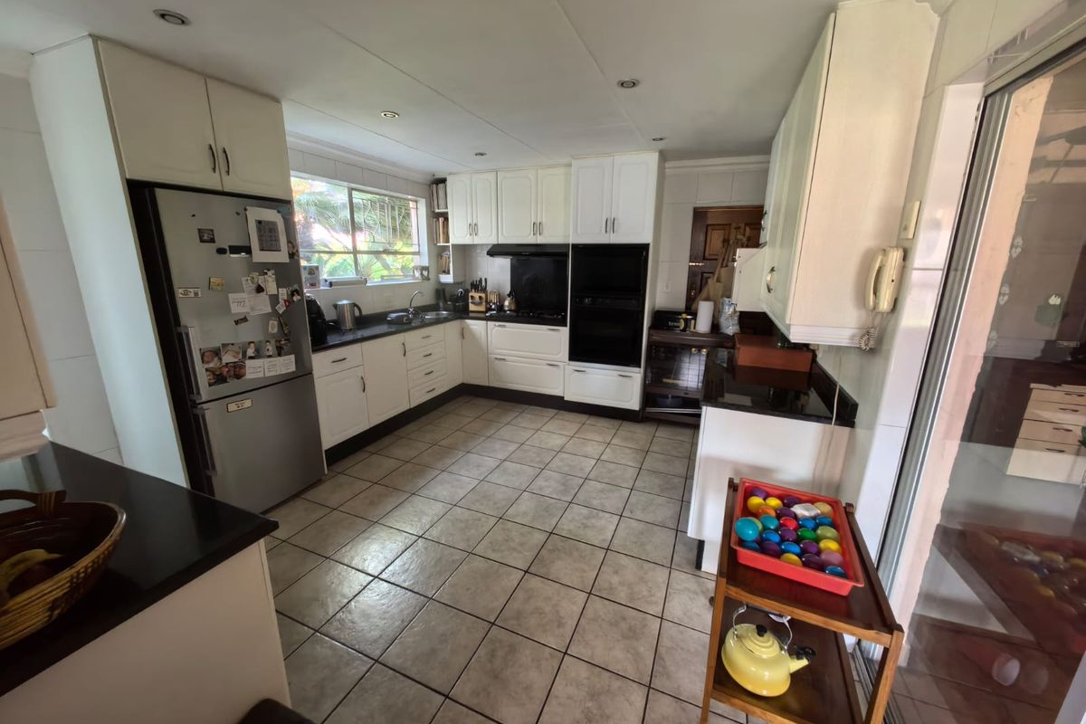 A functional kitchen featuring white cabinetry, dark countertops, built-in oven, and tiled flooring, offering a practical layout for daily meal preparation.