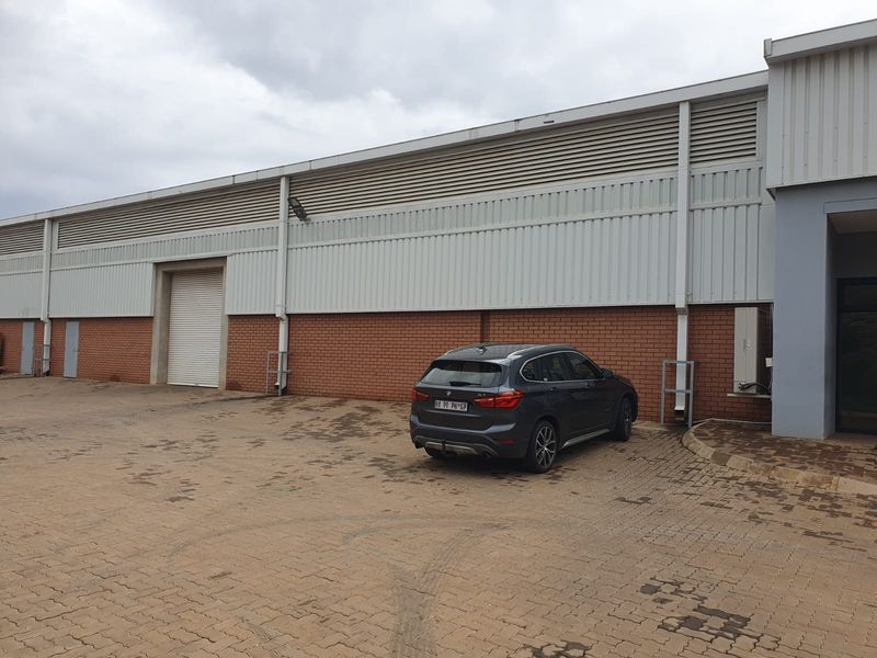 Industrial property exterior featuring a brick and metal clad facade with a roller shutter door and paved driveway access.