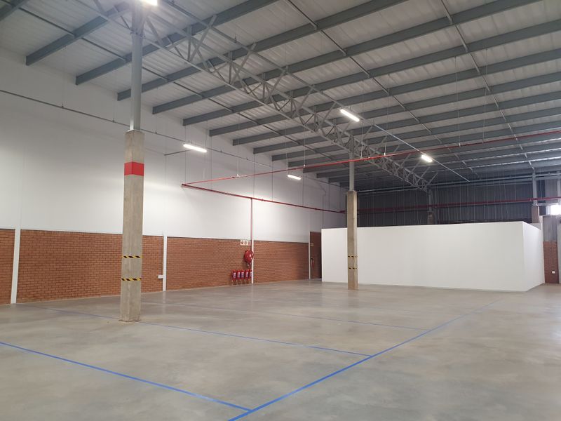 Spacious industrial warehouse unit featuring high ceilings with exposed steel trusses, concrete flooring, and integrated fire safety systems.