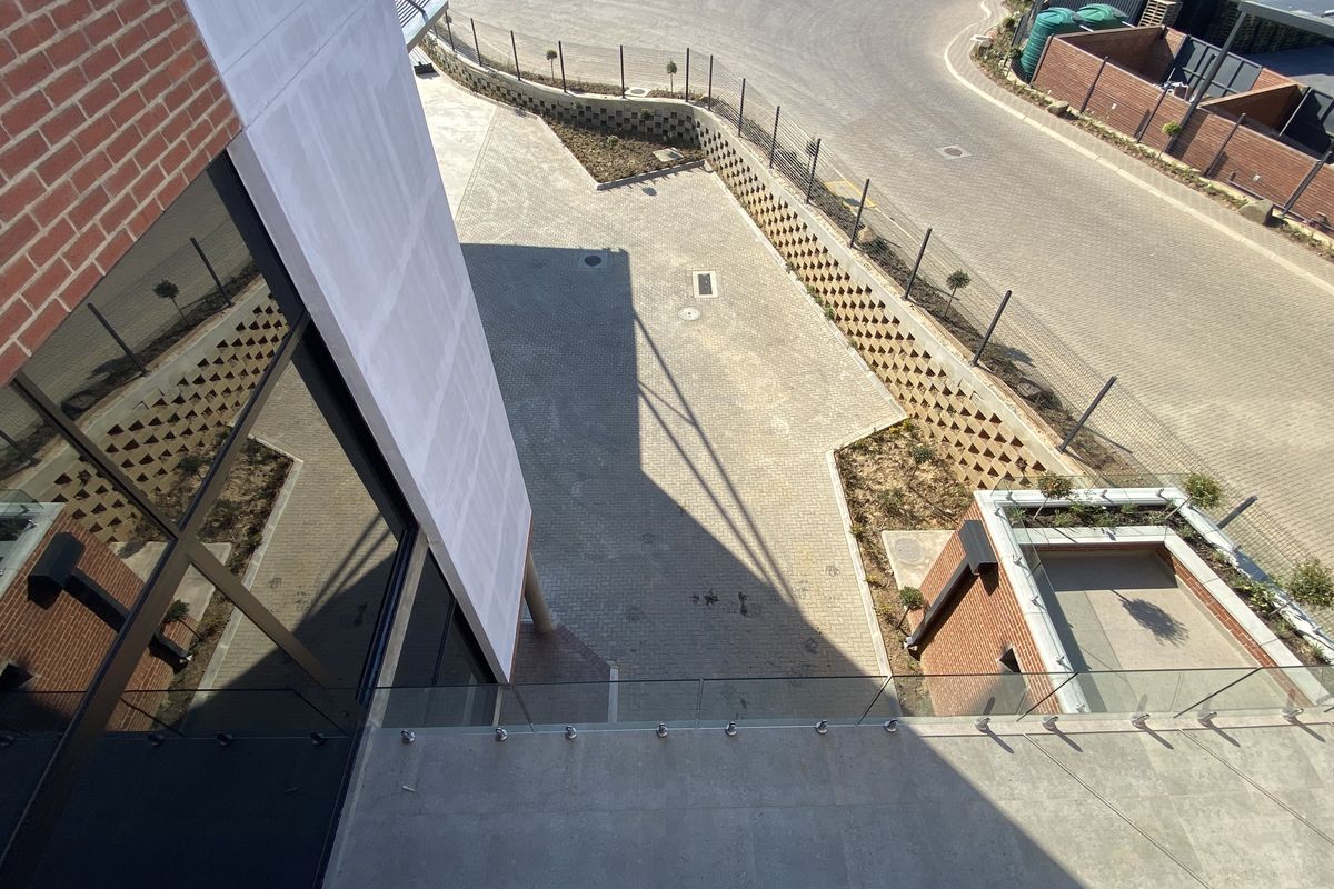 An elevated aerial view of the industrial property exterior, showcasing paved parking areas, retaining walls, and modern brick and glass building facade.