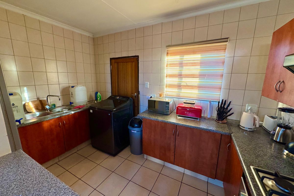 Functional kitchen featuring granite countertops, tiled splashbacks, and built-in cabinetry with integrated laundry plumbing connections.